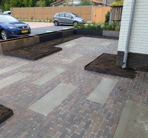 Bloembakken van cortenstaal en gecoat staal. Bestrating van Schellevis tegels en gebakken Dikformaat. Afgevoegd met epoxymortel - Hoveniersbedrijf C.K. van Mourik de hovenier voor West Betuwe, Tiel, Culemborg, Geldermalsen, Buren