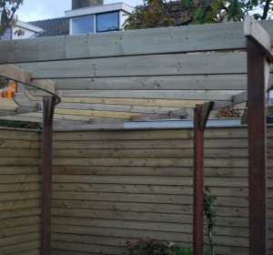 Ronde pergola. De liggers zijn allemaal maatwerk voor deze tuin. Resultaat is heel apart - Hoveniersbedrijf C.K. van Mourik Geldermalsen Tiel Culemborg