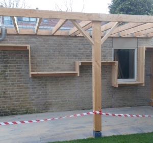 De houtberging tegen de muur: onder het hout en bovenop plaats om iets neer te zetten  - Hoveniersbedrijf C.K. van Mourik West-Betuwe Geldermalsen Tiel Culemborg